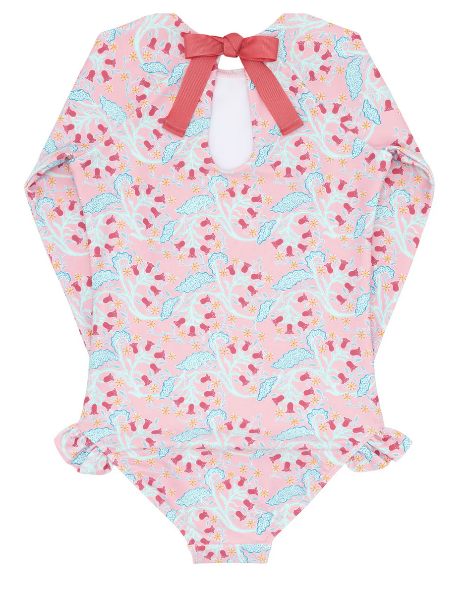 The Minnow Girls' Rashguard One Piece by Minnow is a sun-safe, long-sleeve swimsuit in a pink floral pattern, featuring a delightful keyhole back with a red grosgrain ribbon bow and ruffled leg openings for both style and protection.