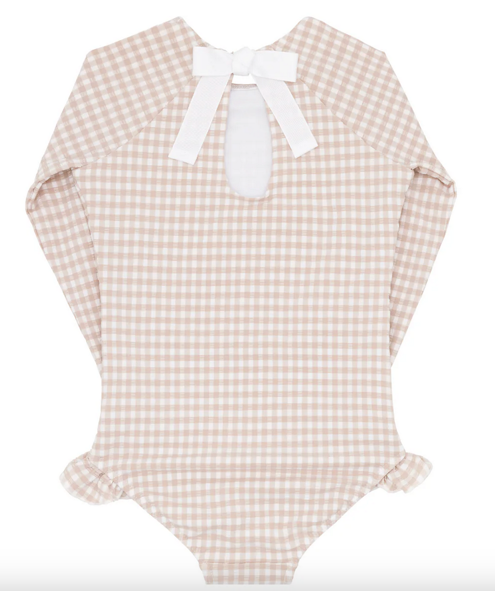 The Minnow Girls' Rashguard One Piece is a beige and white gingham long-sleeve baby bodysuit, highlighted by a charming back bow tie made with grosgrain ribbon and adorned with ruffled leg openings.