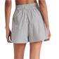 From the back, a person wears Merlette New York's Antibes Stripe Short, featuring a high waist and gray and white pinstripes. The elastic waistband enhances its wide-leg silhouette while their arms rest relaxed at their sides.