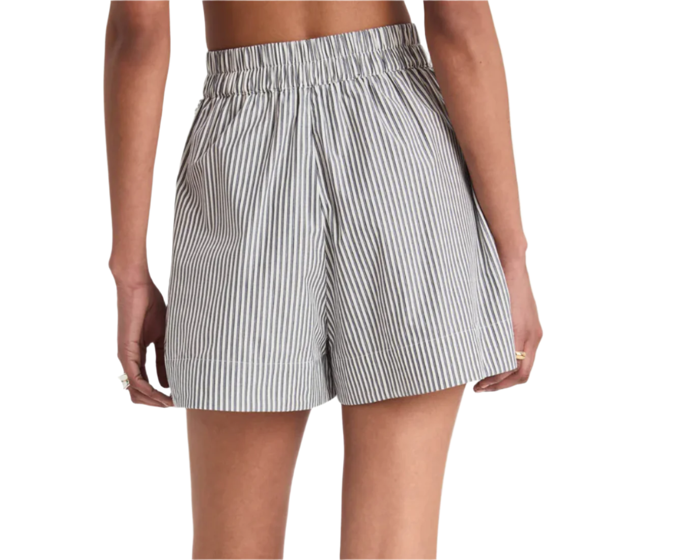 From the back, a person wears Merlette New York's Antibes Stripe Short, featuring a high waist and gray and white pinstripes. The elastic waistband enhances its wide-leg silhouette while their arms rest relaxed at their sides.