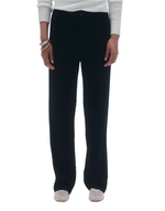 A person wearing black Guest In Residence Cable Cashmere Trousers and a white Jane Cable Cardigan stands with arms relaxed at their sides. This ensemble, by Guest in Residence, is a seasonal favorite, effortlessly combining comfort and style.