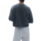 Person wearing a Guest in Residence Grizzly Cashmere Cardigan exudes a contemporary knit style, paired with light cable-knit pants, standing with their back facing the camera.