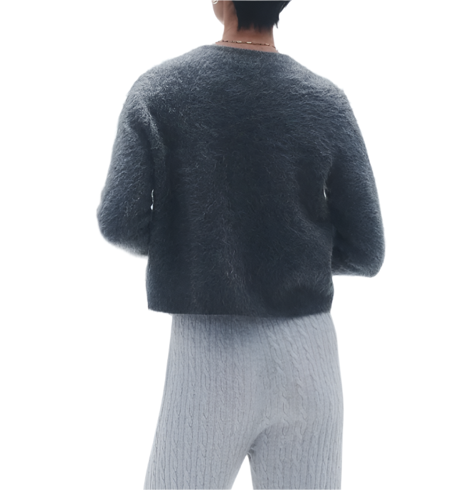 Person wearing a Guest in Residence Grizzly Cashmere Cardigan exudes a contemporary knit style, paired with light cable-knit pants, standing with their back facing the camera.