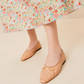 A person standing gracefully on a light surface showcases the Loeffler Randall Landry Woven Flats, paired with the elegant lower part of a floral skirt.