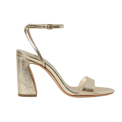 The Loeffler Randall Malia Curved Heel Sandal, crafted from champagne metallic leather, features an adjustable ankle strap and open toe design with a chic curved heel.