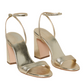 The Loeffler Randall Malia Curved Heel Sandal, from Loeffler Randall, features gold high-heeled sandals with adjustable ankle straps, open toes, and a chic block heel in champagne metallic leather.