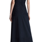 A person is seen from the back, wearing the Lela Rose Poplin V-Neck Dress. This long, dark blue dress features elegant lace-paneled details and an A-line silhouette that provides a graceful flair, complemented by black shoes.