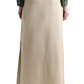 Back view of a person wearing the Altuzarra Mack Skirt, an Italian-made long beige skirt with a voluminous silhouette, two back pockets, and side slits, paired with a green jacket.