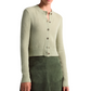 A person wearing the Altuzarra Thea Sweater, a merino wool-blend light green button-up cardigan with ribbed edges, and an olive green skirt, shown from the shoulders to mid-thigh.