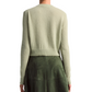 Back view of a person wearing an Altuzarra Thea Sweater in merino wool-blend light green with ribbed edges, paired with a dark green skirt.