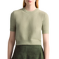 A person is wearing the Altuzarra Ty Sweater, a light green short-sleeve top with a ribbed hem, paired with a dark green skirt. Both items feature a close-fitting silhouette and the entire ensemble is set against a white background.