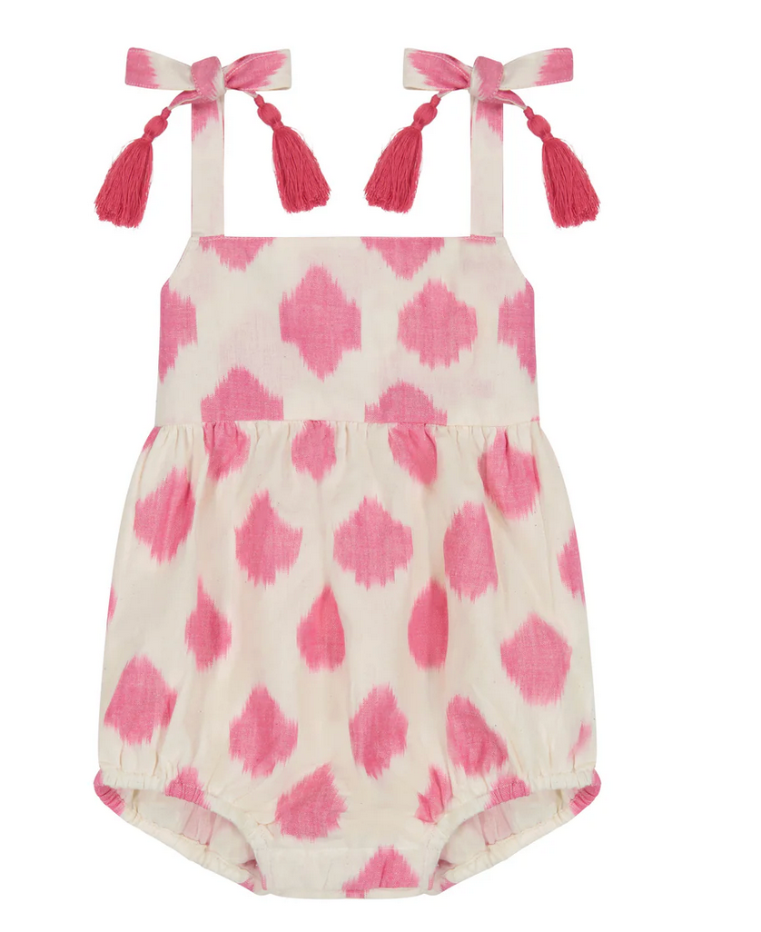 The Mer St Barth Zoe Romper by Mer is a charming pink and white patterned baby romper with shoulder straps and tassel bows, perfect as a playful summer staple.