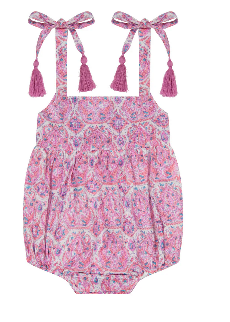 The Mer St Barth Zoe Romper by Mer is a perfect summer staple with pink and purple patterns, shoulder ties, tassel detailing, and two charming adjustable straps with bows.