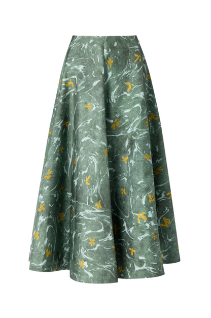 The Altuzarra Varda Skirt is a high-waisted, knee-length green midi with a flared silhouette and a marbled floral print featuring white and yellow accents, crafted in Italy for timeless elegance.