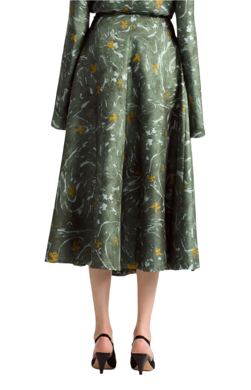 A woman in the Altuzarra Varda Skirt, featuring a green marbled floral print and knee-length midi silhouette, paired with a matching long-sleeve top and black low-heeled shoes.