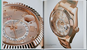 An open book from Graphic Image displays images of two exquisite rose gold Rolex Sky-Dweller wristwatches with Roman numerals and dual time zones on glossy pages, evoking vintage style.