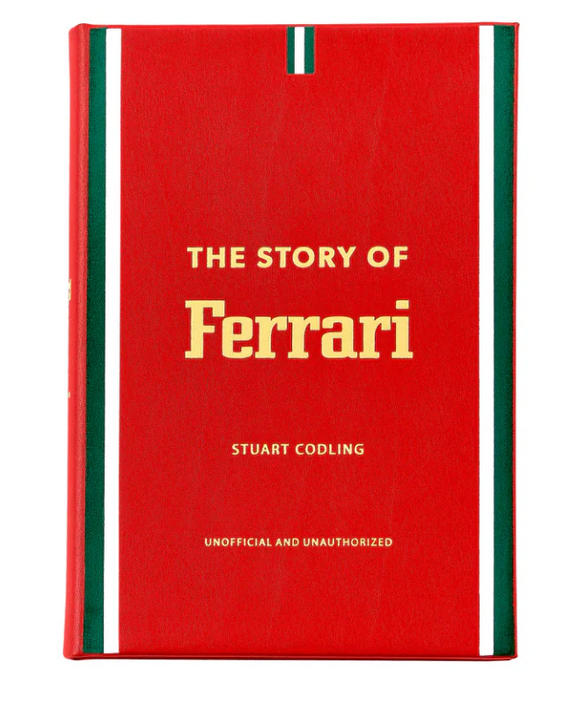 The red leather book "The Story of Ferrari" by Graphic Image explores the thrilling world of motorsport and luxury cars, featuring green and white striped edges.