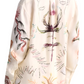 A person is wearing the Altuzarra Chika Top, a long-sleeve cream shirt featuring colorful abstract and nature-inspired designs on the back and sleeves. With its button front closure, this top exudes relaxed sophistication and an effortlessly chic style.