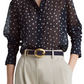 A person wears a sheer navy polka dot blouse tucked into high-waisted beige trousers, cinched with the Altuzarra Vintage Brass Buckle Belt.