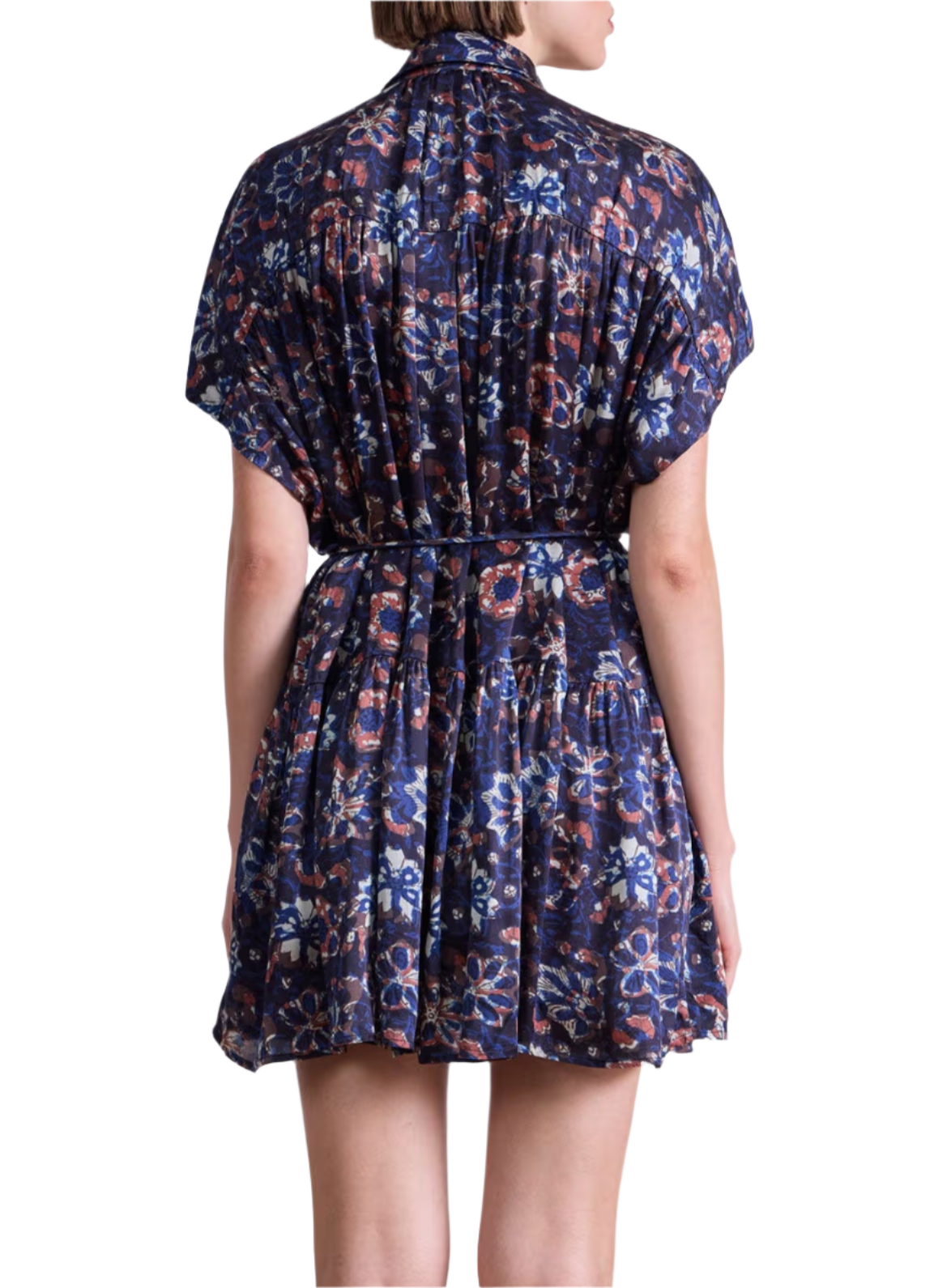 A person is shown from the back wearing the Agnezca Mini Dress by Apiece Apart—a short, loose-fitting, dark blue summer floral dress with a self-tie belt for a cinched waist and flowy silhouette.