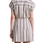 A woman in the Apiece Apart San Vito Sarong Dress, a short-sleeved, collared striped mini dress with a flattering fit, stands facing away from the camera wearing sunglasses.