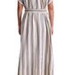 A woman, seen from behind, wears the Apiece Apart Isola Caftan Dress—a calf-length, short-sleeve style with vertical brown and white stripes and a matching belt—teamed with brown sandals.