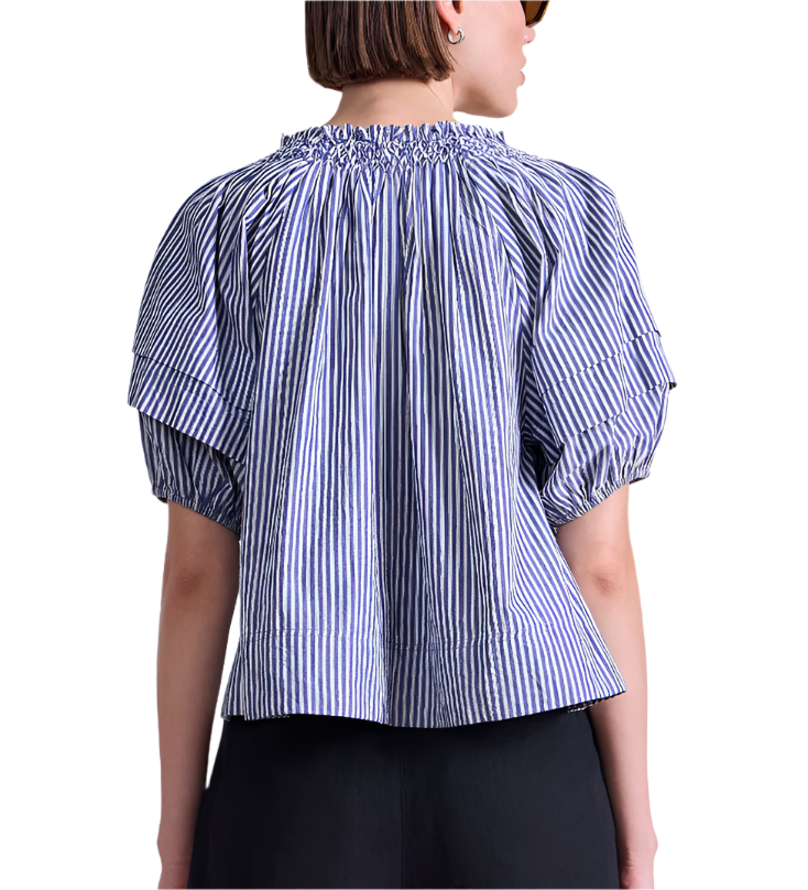 A person seen from the back wears the Apiece Apart Caminitas Puff Sleeve Top, a blue and white classic striped blouse with gathered neckline—ideal for effortless summer style.