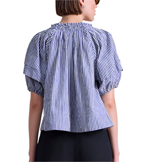 A person seen from the back wears the Apiece Apart Caminitas Puff Sleeve Top, a blue and white classic striped blouse with gathered neckline—ideal for effortless summer style.