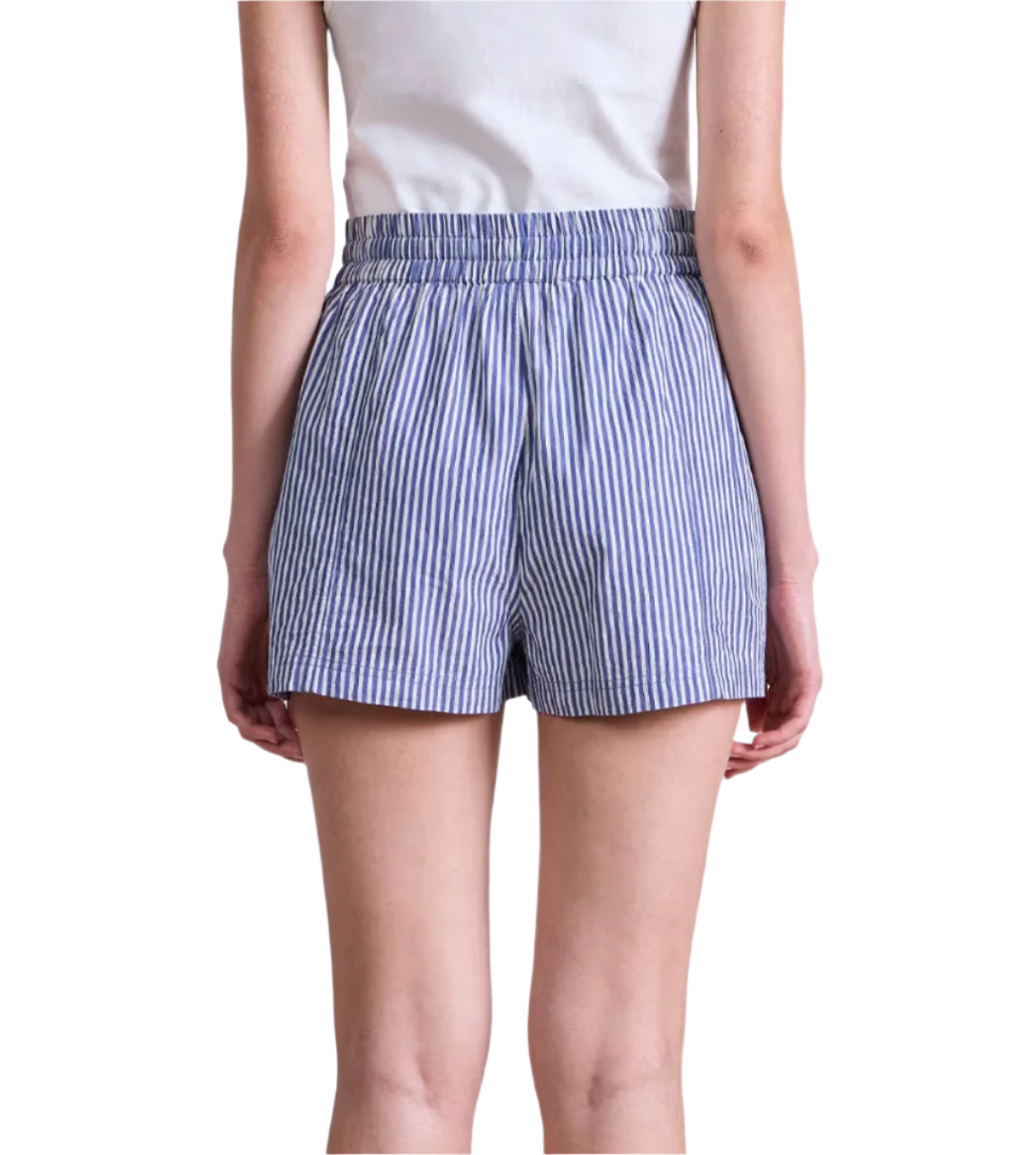 Model wearing Apiece Apart Surf Shorts—blue-and-white vertical stripes, pull-on style—paired with a white shirt and shown from the back against a plain background; perfect for warm days.