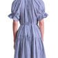 A woman is seen from the back wearing the Apiece Apart Marza Mini Dress, a short-sleeved blue and white striped mini dress with a belted waist.