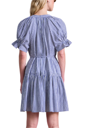 A woman is seen from the back wearing the Apiece Apart Marza Mini Dress, a short-sleeved blue and white striped mini dress with a belted waist.