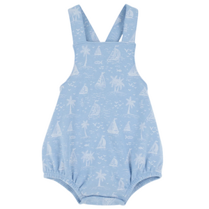 The Beaufort Bonnet Company Baby Stillman Sunsuit is a light blue romper with white sailboats, palm trees, and fish prints, featuring shoulder straps and elastic leg openings in the brand’s classic style.