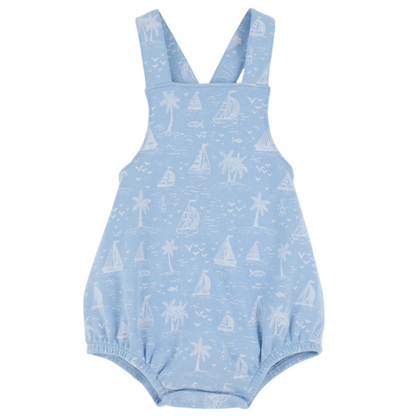 The Beaufort Bonnet Company Baby Stillman Sunsuit is a light blue romper with white sailboats, palm trees, and fish prints, featuring shoulder straps and elastic leg openings in the brand’s classic style.