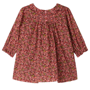 The Bonpoint Baby Girls' and Girls' Juju Smocked Dress, made with Liberty Fabrics in organic cotton, features long sleeves, chest smocking, gathered fabric, and a red, pink, and green floral print.