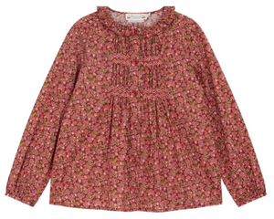 The Bonpoint Girls' Gentille Smocked and Embroidered Blouse is crafted from Liberty organic cotton with floral patterns, a ruffled neckline, and gathered front detailing in pink and red tones.