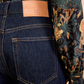 Wearing Ulla Johnson’s Genevieve High Rise Jean in vintage-inspired indigo with a tan patch, paired with a floral patterned shirt.