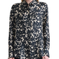 A woman wearing the Chika Top by Altuzarra—a relaxed, long-sleeve silk blouse with a black and white abstract spotted pattern and concealed buttons—stands against a plain background.
