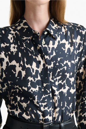 A person wearing the Altuzarra Chika Top—a relaxed, black and white abstract animal print silk shirt with a concealed button front—paired with a black belt.