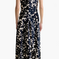 A woman faces away, wearing the Altuzarra Drina Dress with a black and white abstract print, paired with tan high-heeled shoes.