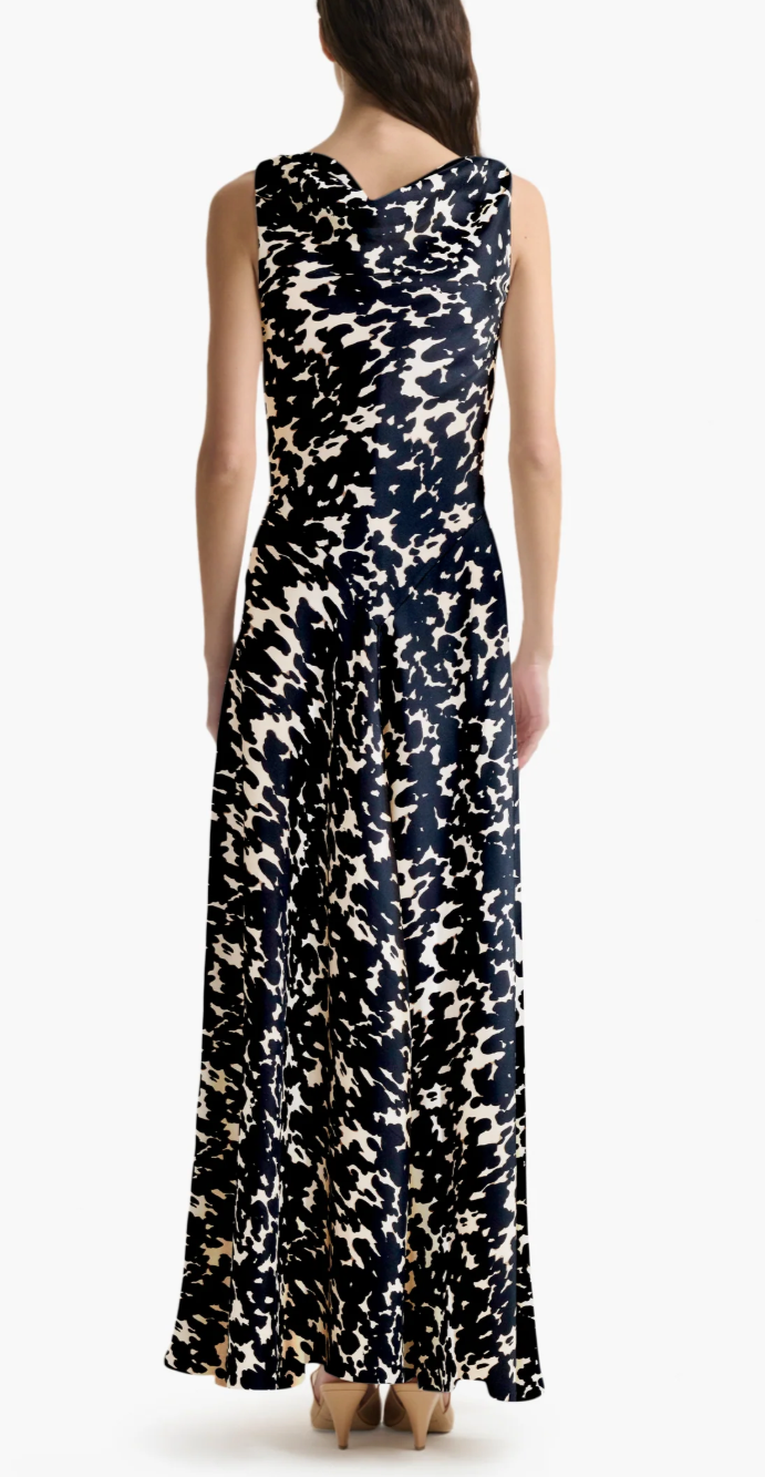A woman faces away, wearing the Altuzarra Drina Dress with a black and white abstract print, paired with tan high-heeled shoes.
