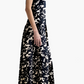 A woman in profile models the Altuzarra Drina Dress, a sleeveless, floor-length black-and-white abstract silk gown, paired with beige heels against a plain white background.