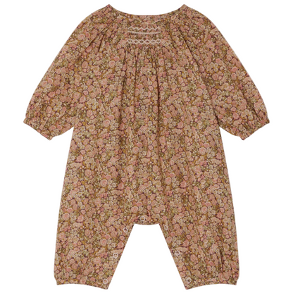 The Bonpoint Baby Girls' Jia Smocked Jumpsuit in Liberty Fabric features long sleeves, a pink and brown floral print, gathered neckline, elastic cuffs, hand-embroidered smocking, and snaps at the legs.