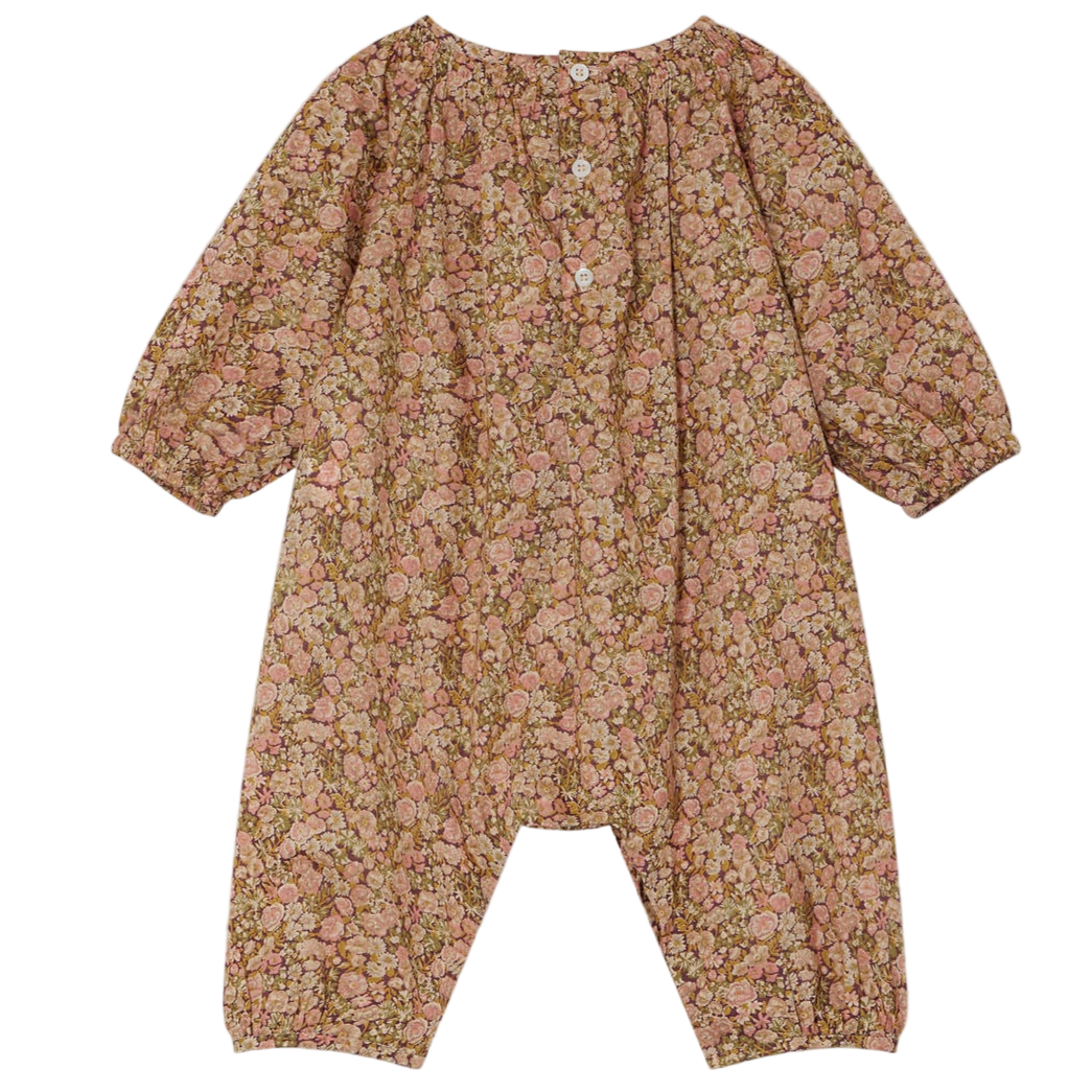 The Baby Girls' Jia Smocked Jumpsuit in Liberty Fabric by Bonpoint is a long-sleeved, floral romper with three white front buttons and elastic cuffs at the sleeves and ankles.