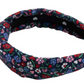 The Beaufort Bonnet Company’s T.B.B.C. x Lele Sadoughi Knotted Headband features a padded design with a navy base and vibrant red, pink, white, and green floral print, inspired by Lele Sadoughi’s signature style.