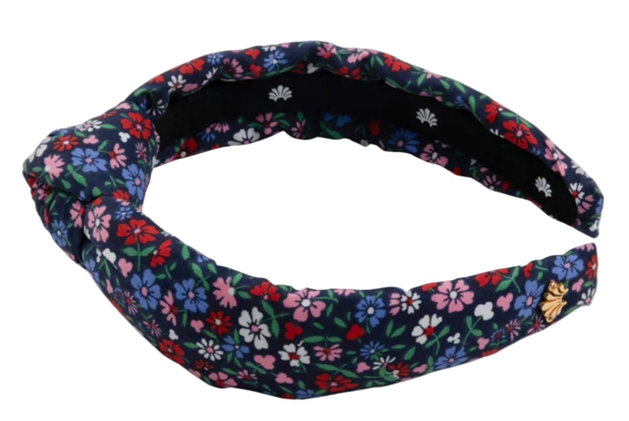 The Beaufort Bonnet Company’s T.B.B.C. x Lele Sadoughi Knotted Headband features a padded design with a navy base and vibrant red, pink, white, and green floral print, inspired by Lele Sadoughi’s signature style.