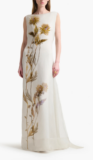 A woman wearing the Altuzarra Jools Dress, a sleeveless, floor-length silk gown featuring a bold, realistic thistle flower print on the front.