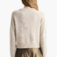 A person with long hair wears the Altuzarra Paulie Sweater, featuring delicate floral embroidery and beads, styled with a khaki skirt and photographed from behind against a plain background.