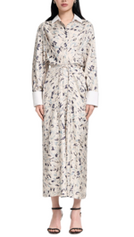 A person wearing the Altuzarra Floyd Dress, featuring an abstract animal pattern in a collared shirt silhouette with a waist tie, paired with black heeled sandals.