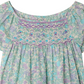 The Bonpoint Girls' Grenade Smocked Blouse features detailed chest smocking and embroidery in pastel purple, blue, and green tones, beautifully crafted from Liberty fabric.