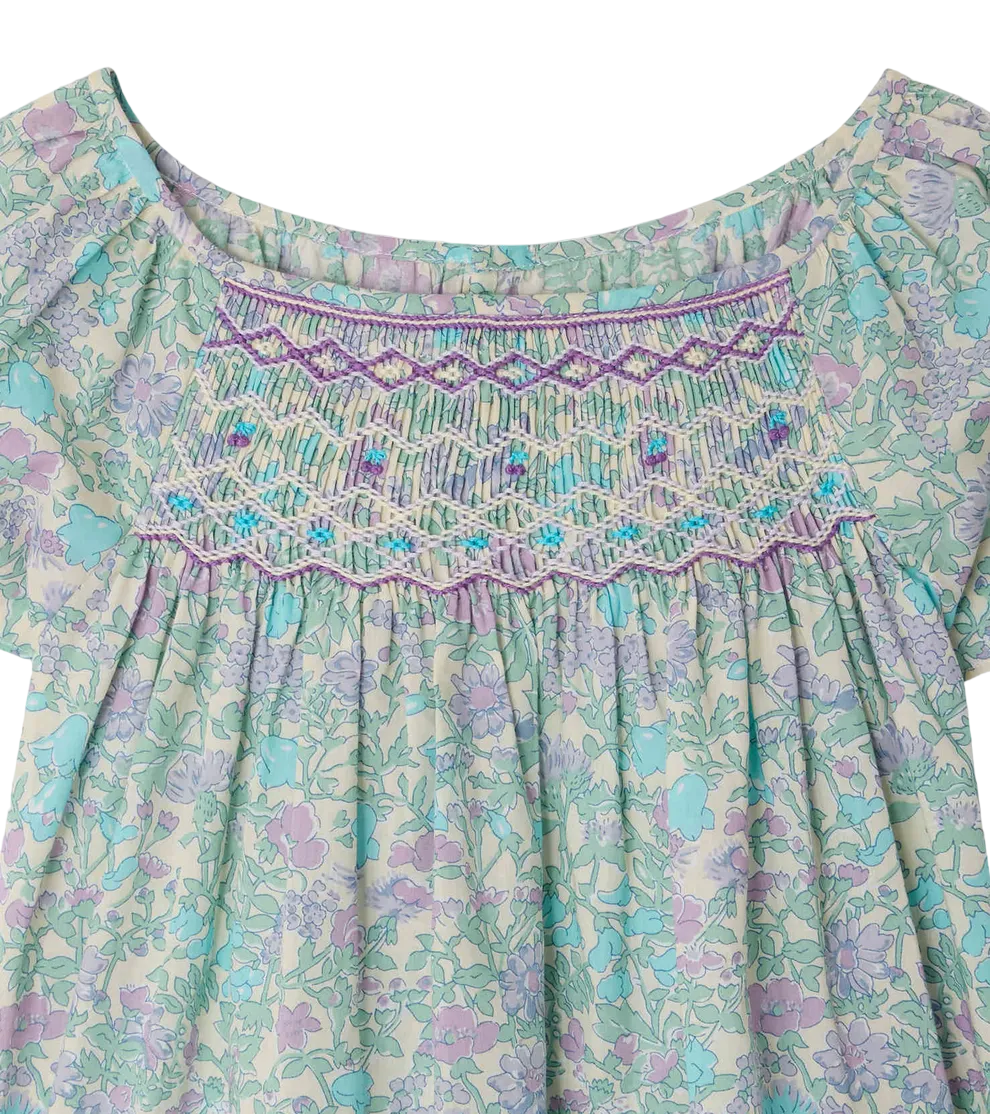 The Bonpoint Girls' Grenade Smocked Blouse features detailed chest smocking and embroidery in pastel purple, blue, and green tones, beautifully crafted from Liberty fabric.